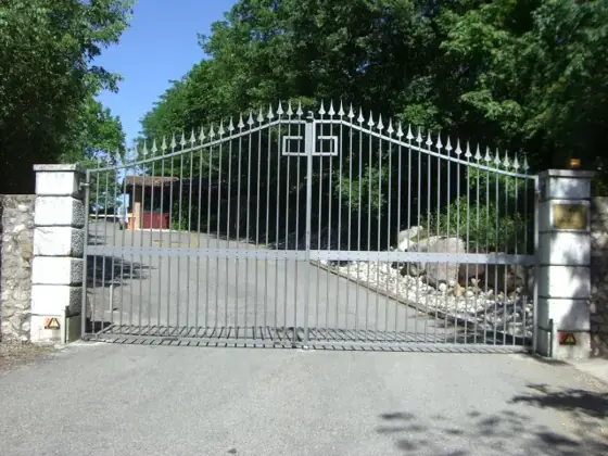 Cancello automatico a due ante ad arco con lampeggiante sul pilastro